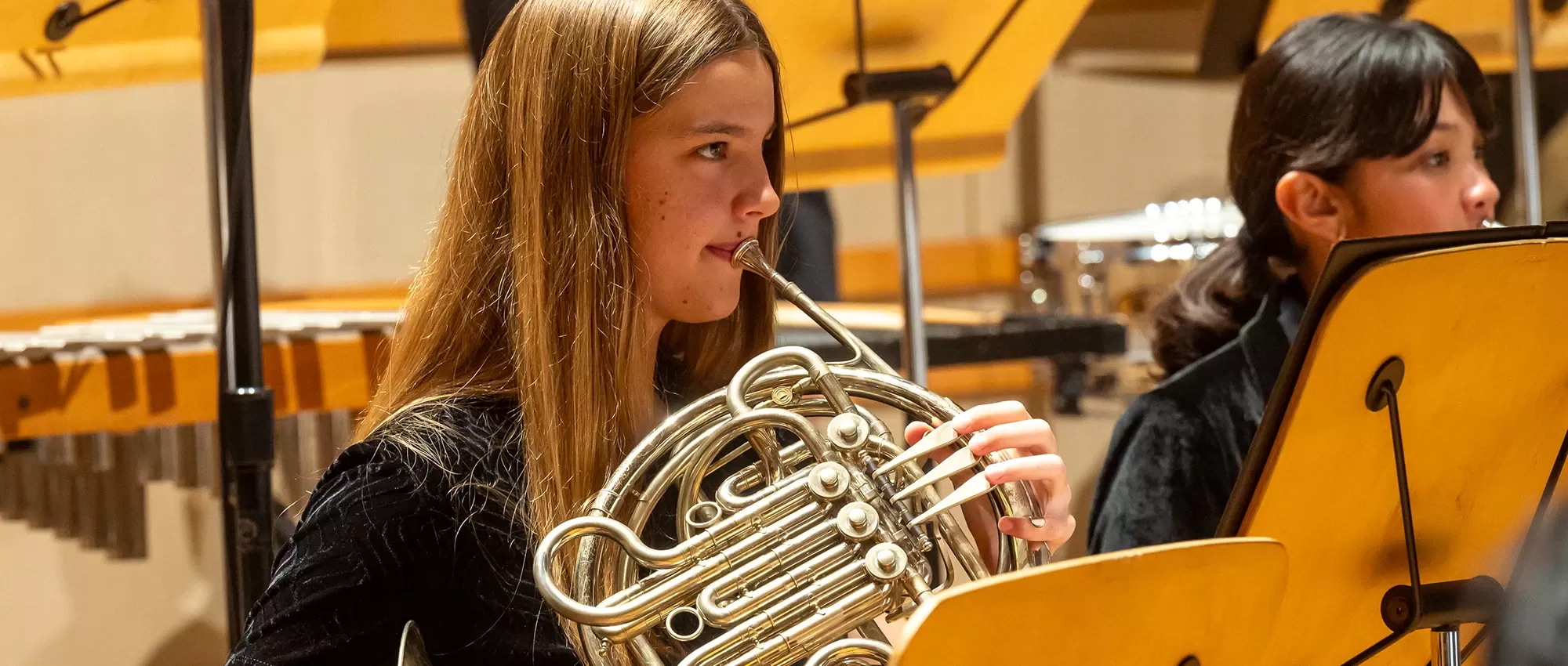 A young, blond horn player performing in Pacific Symphony Youth Orchestra