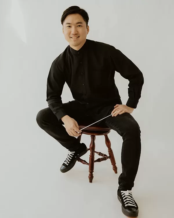 Assistant Conductor Moon Doh seated and smiling at the camera