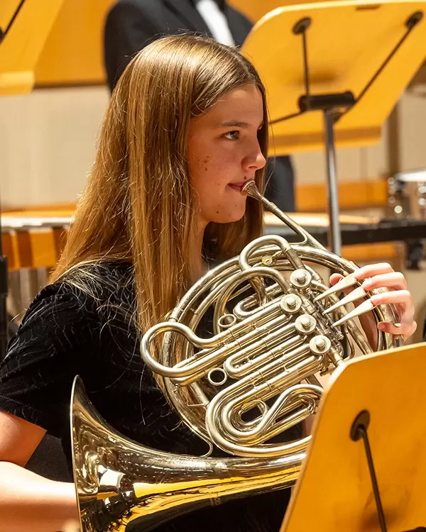 A young, blond horn player performing in Pacific Symphony Youth Orchestra