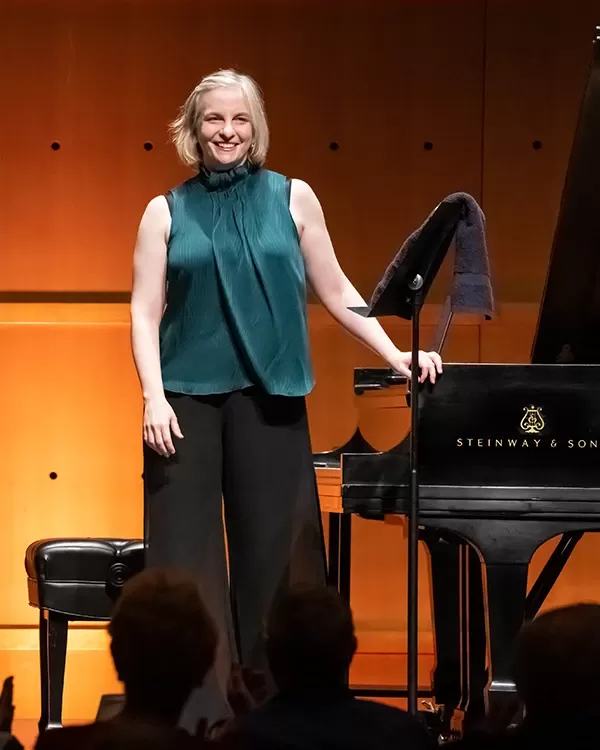 Female pianist standing next to her instrument
