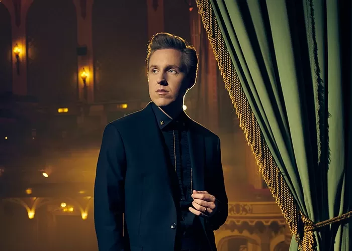 Cody Fry next to a green curtain