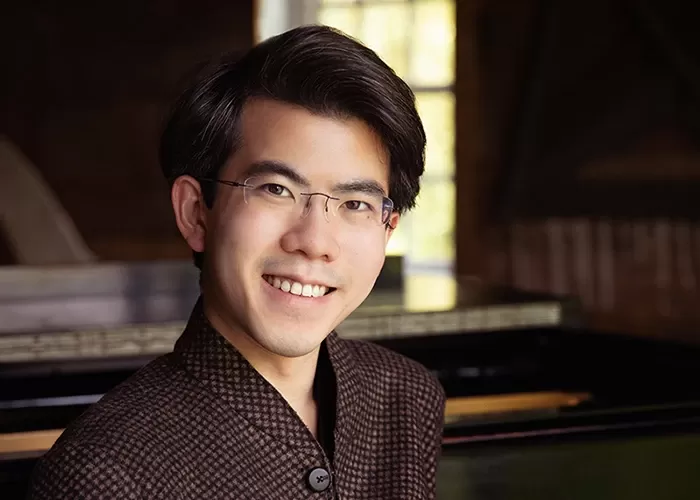 Aristo Sham in front of a piano