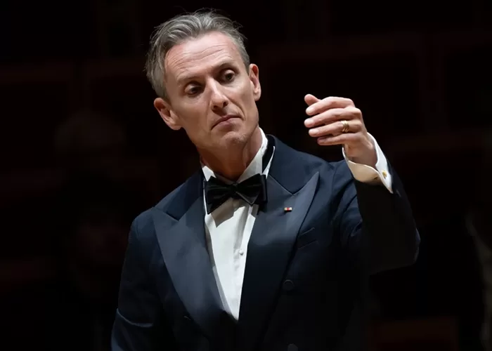 Violinist Aubrey Oliversion with long blond hair weating a yellow/orange dress