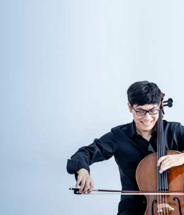 A young cellist looking down at his instrument