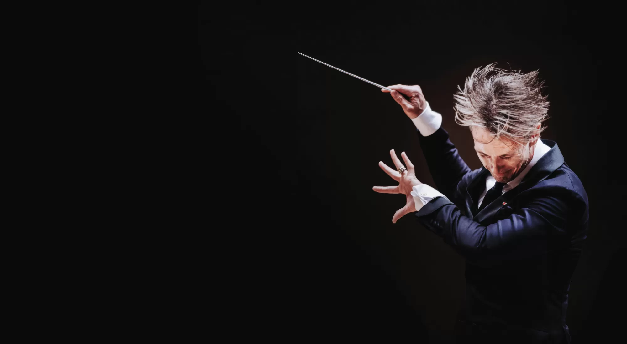 Music Director Alexander Shelley conducting with his hair flying in the air