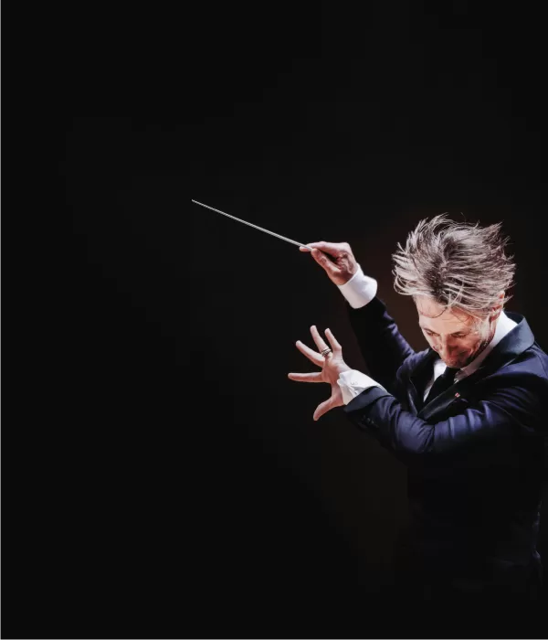 Music Director Alexander Shelley conducting with his hair flying in the air