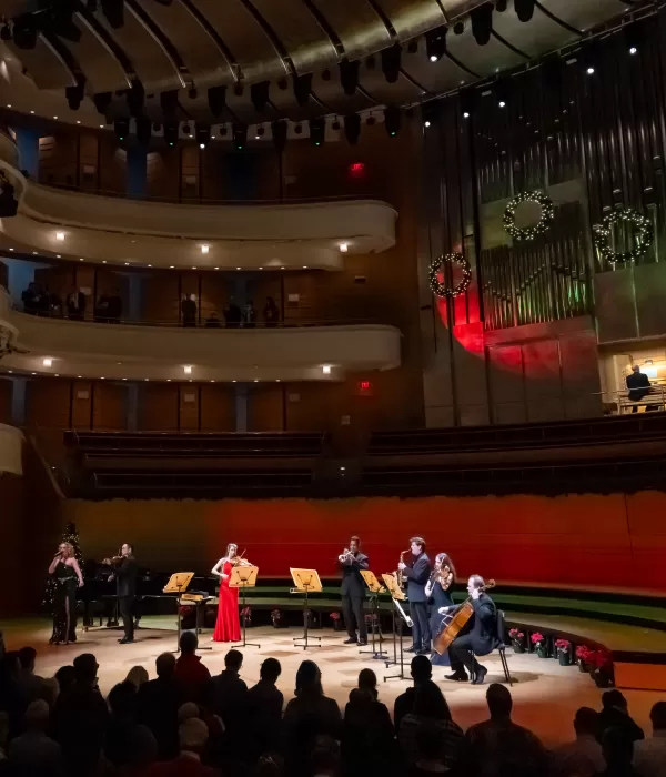 Several Pacific Symphony musicians on the concert hall stage with someone playing the organ behind them