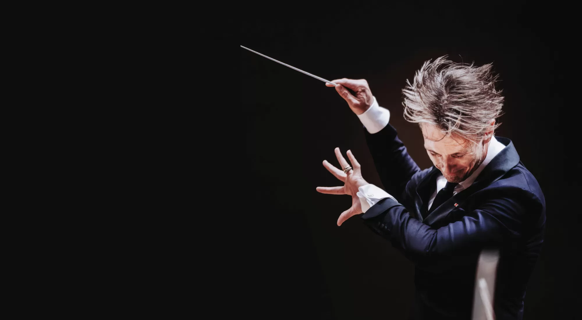 Music Director Alexander Shelley conducting with his hair flying in the air