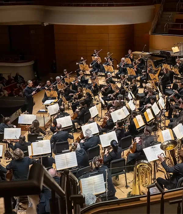 Pacific Symphony on stage with Alexander Shelley conducting viewed from behind the orchestra