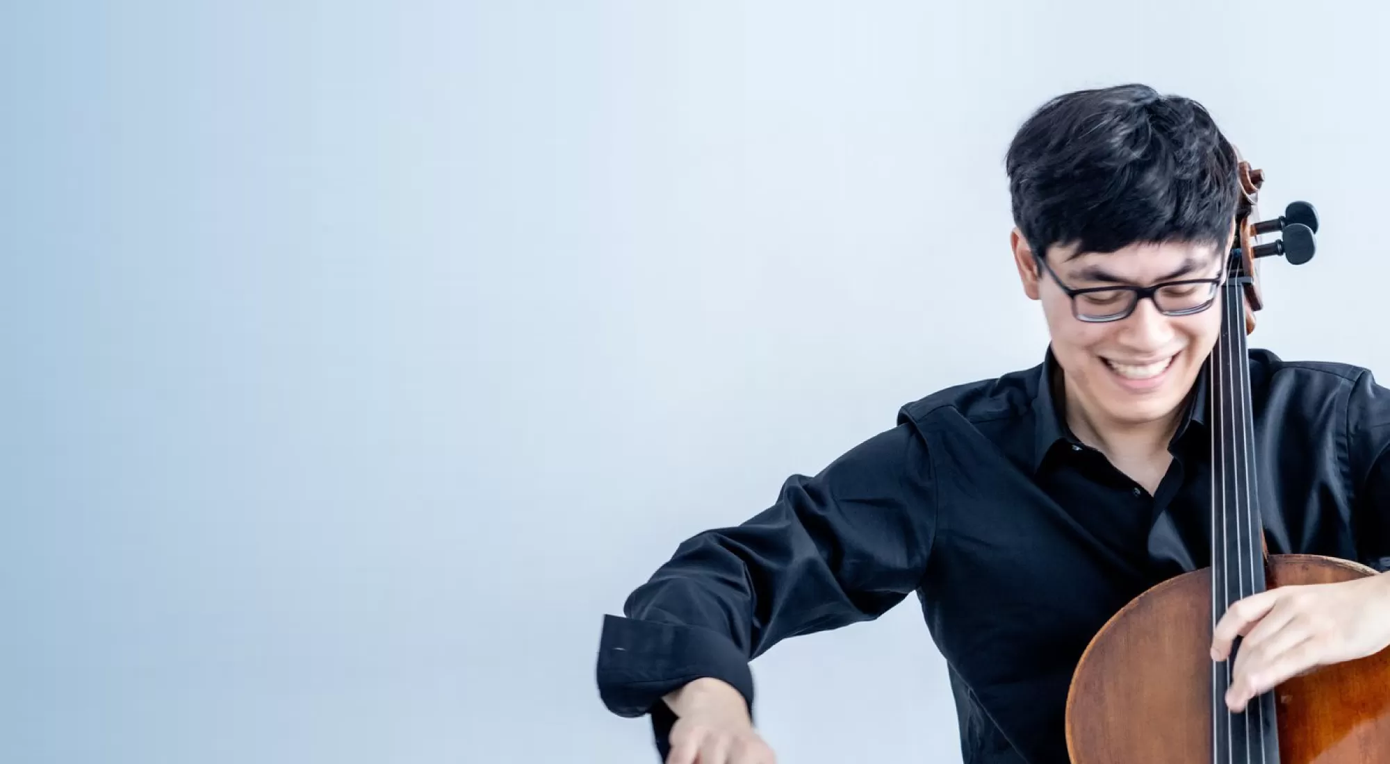 A young cellist looking down at his instrument