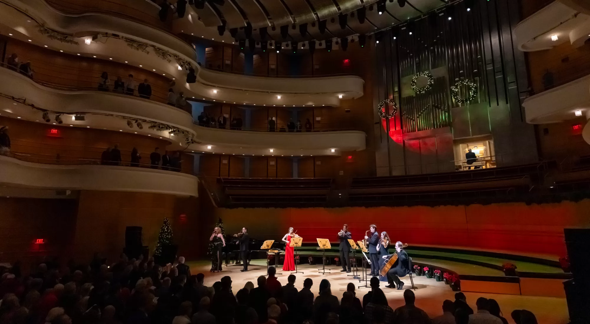 Several Pacific Symphony musicians on the concert hall stage with someone playing the organ behind them